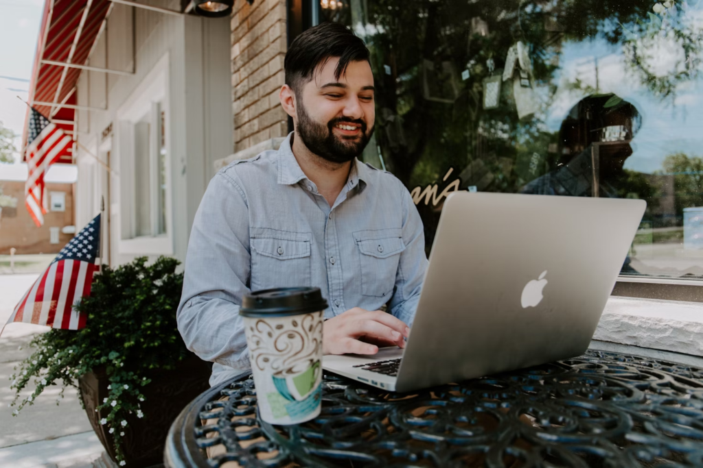 Man working happily on laptop at outdoor cafe – symbol of passive income lifestyle and financial freedom in 2025